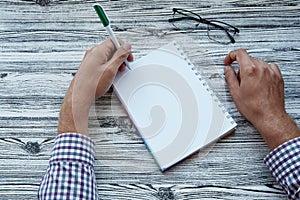 Man writing in notepad mock up, using his left hand. Conceptual photo of lefthanded day. Copy space.