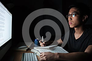 Man writing in notepad and using computer