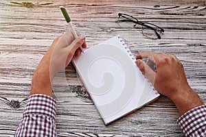 Man writing in notepad, using his left hand. Conceptual photo of lefthanded day. Mock up notepad. Top view. Copy space.