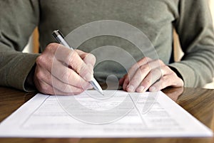 Man Writing on Paper with Pen on Table