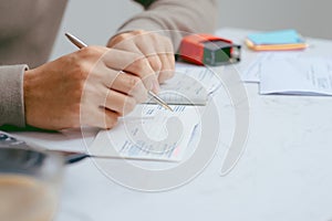 Man writing a payment check at the table with calculator and sta