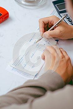 Man writing a payment check at the table with calculator and stamp