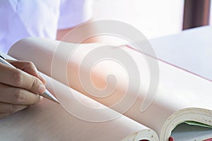 Man writing pen in book on white table