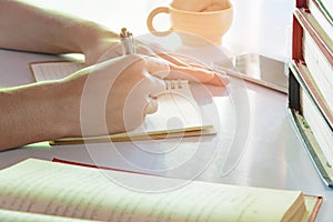 Man writing pen in book on white table