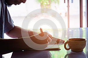 Man writing pen in book on white table