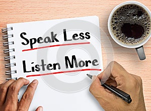 Man writing quote Speak less listen more on notebook with coffee on wood table background