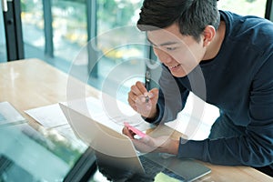 Man writing reminder on sticky note. male freelancer student working organizing plan at workplace