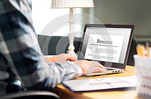 Man writing resume and CV in home office with laptop photo