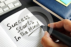 Man is writing Success starts in the mind in a note.