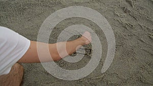 Man is writing a text on the sand of the beach