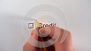 Man writing a tick in checkbox CREDIT on white paper. Credit Worthiness