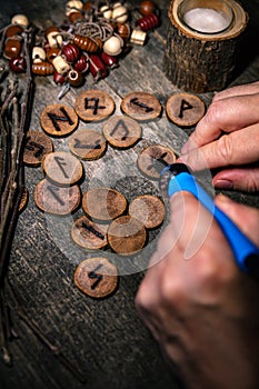 Man writing wooden runes with an pyrography or pokerwork, esoteric background