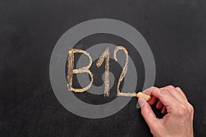 Man writing word B12 on chalkboard