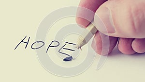 Man writing the word Hope on notepaper