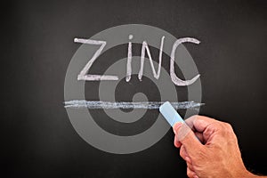 Man writing the word Zinc on a chalkboard