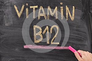 Man writing words Vitamin B12 on chalkboard