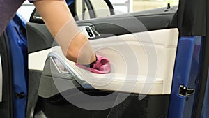 A man& x27;s hand cleans the door of a new car with a rag.