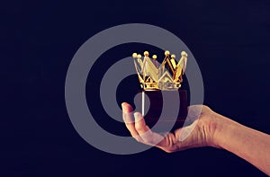 Man& x27;s hand holding crown award trophy for show victory or winning first place. Glitter overlay. photo