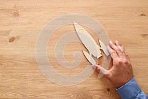 man& x27;s hand holding rocket over wooden background.