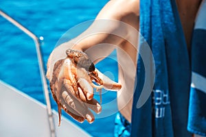Man on a yacht, he caught an octopus from the sea.