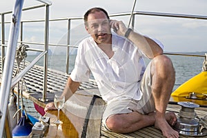 Man on yacht with mobile phone and wine