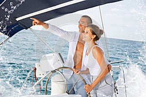 Man on yacht wheel pointing to horizon