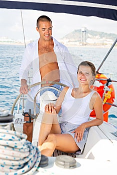Man at yacht wheel during sea vacation with woman