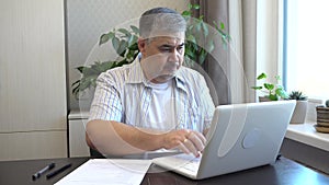 Man Yawning While Working at Home on a Computer