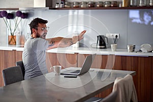 Man yawns in the morning while checking email on a laptop photo
