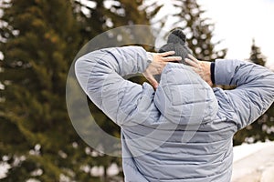 Man yawns / stretches in the park in winter