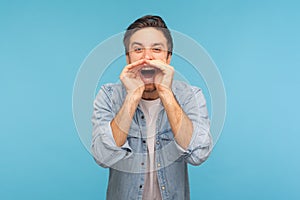 Man yelling widely opening mouth holding hands on face, screaming announcing his opinion.