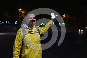 Man in yellow coat holding mobile phone in hand