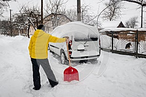 A man in yellow digs a car out of the snow