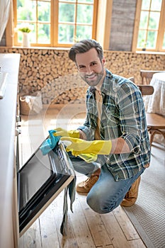 Man in yellow gloves cleaning the surface in the kitchen and feeling good