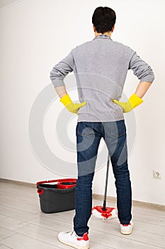 Man with Yellow Gloves and Mop in White Room