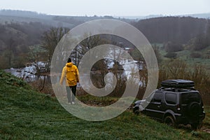 A man in a yellow jacket with his off-road vehicle. A small compact car with four-wheel drive for extreme hobbies and recreation