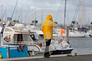 man in yellow oilskin walking along the fishing port