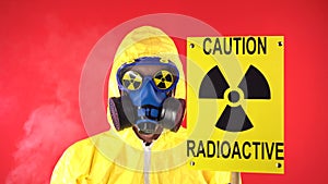 Man in Yellow Protective Suit, Protective Mask waves poster. Caution radiation. Studio video, Behind a man smoke