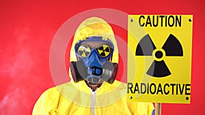 Man in Yellow Protective Suit, Protective Mask waves poster. Caution radiation. Studio video, Behind a man smoke