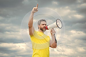 man in yellow shirt agitate in loudspeaker on sky background photo