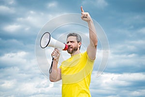man in yellow shirt agitate in loudspeaker on sky background photo