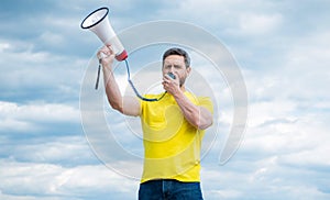 man in yellow shirt shouting in loudspeaker on sky background