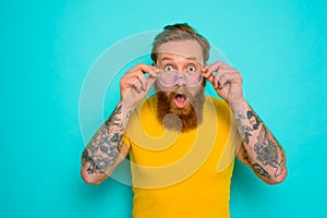 Man with yellow t-shirt and beard is shocked about something