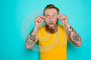 Man with yellow t-shirt and beard is shocked about something