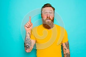 Man with yellow t-shirt and beard is shocked about something