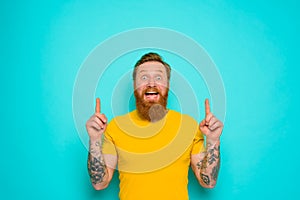 Man with yellow t-shirt and beard is shocked about something