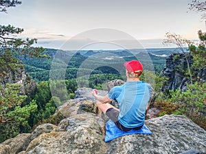 Man in yoga position in mountains above wild nature at sunset. Concept of meditation, spirituality and soul balance