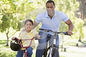 Man and young boy on bikes outdoors smiling