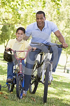 Man and young boy on bikes outdoors smiling