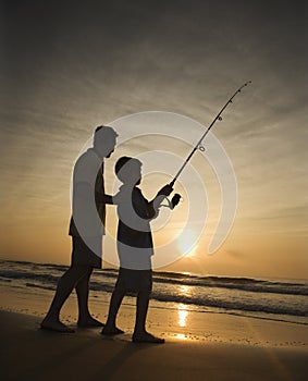 Man and young boy fishing in surf